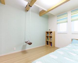 壁紙の爽やかな色と天井の大きな梁に下がったブランコが印象的な子供部屋