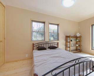 自然素材を使用した室内にバルコニーからの光が優しく映える主寝室